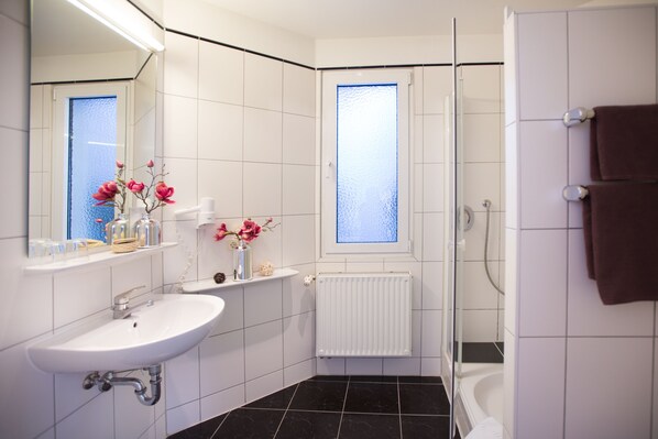 A modern bathroom with a white sink, mirror, and shower. - Hotel und Restaurant Rose (Bietigheim-Bissingen)