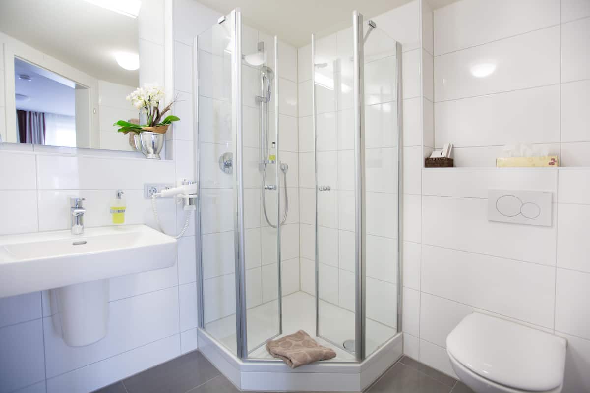 Ein modernes Badezimmer mit einer Duschkabine, einem weißen Waschbecken und einer Toilette.