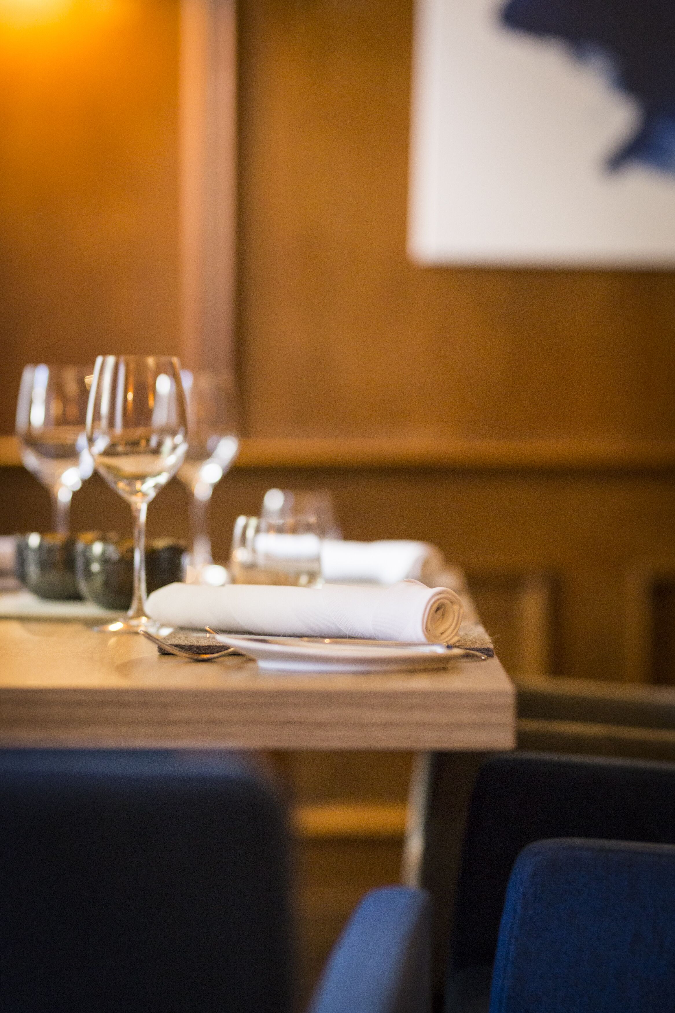 Una mesa de comedor con copas de vino, un mantel enrollado y cubiertos.