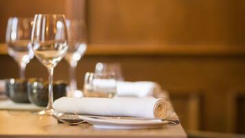 Una mesa de comedor con copas de vino, un mantel enrollado y cubiertos.