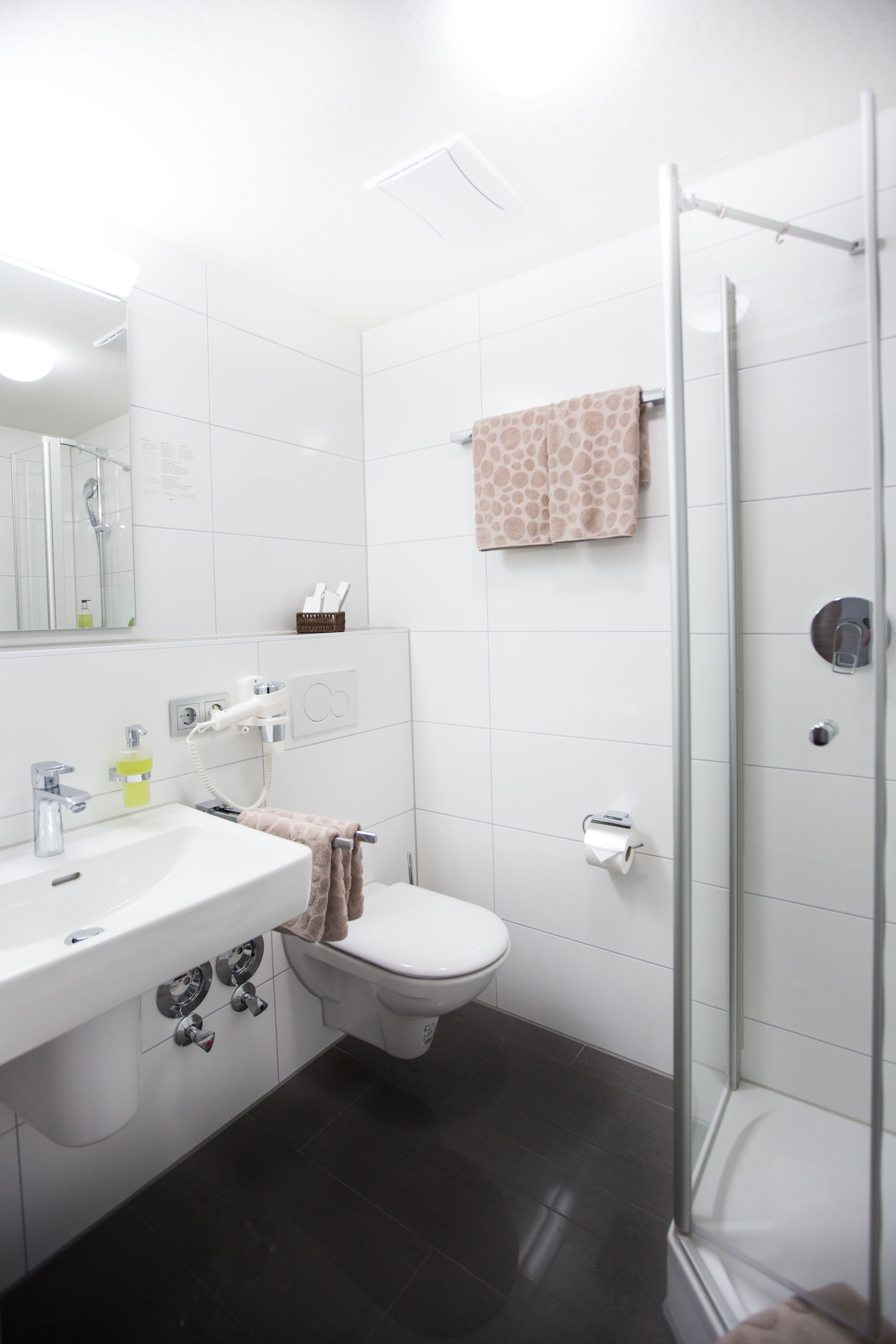 Une salle de bain moderne avec un lavabo blanc, des toilettes et une douche à parois de verre.