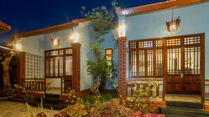 A traditional building with wooden doors and windows, a brick entrance, and a small garden area with plants. - Betel Garden Villas (Da Nang)