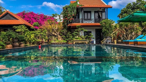 A swimming pool with a reflection of the surrounding buildings and trees. - Betel Garden Villas (Da Nang)