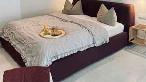 A modern bedroom with a large bed, a round mirror, and a hanging wall decoration. - Hotel-Bistro-Europa (Merchweiler)