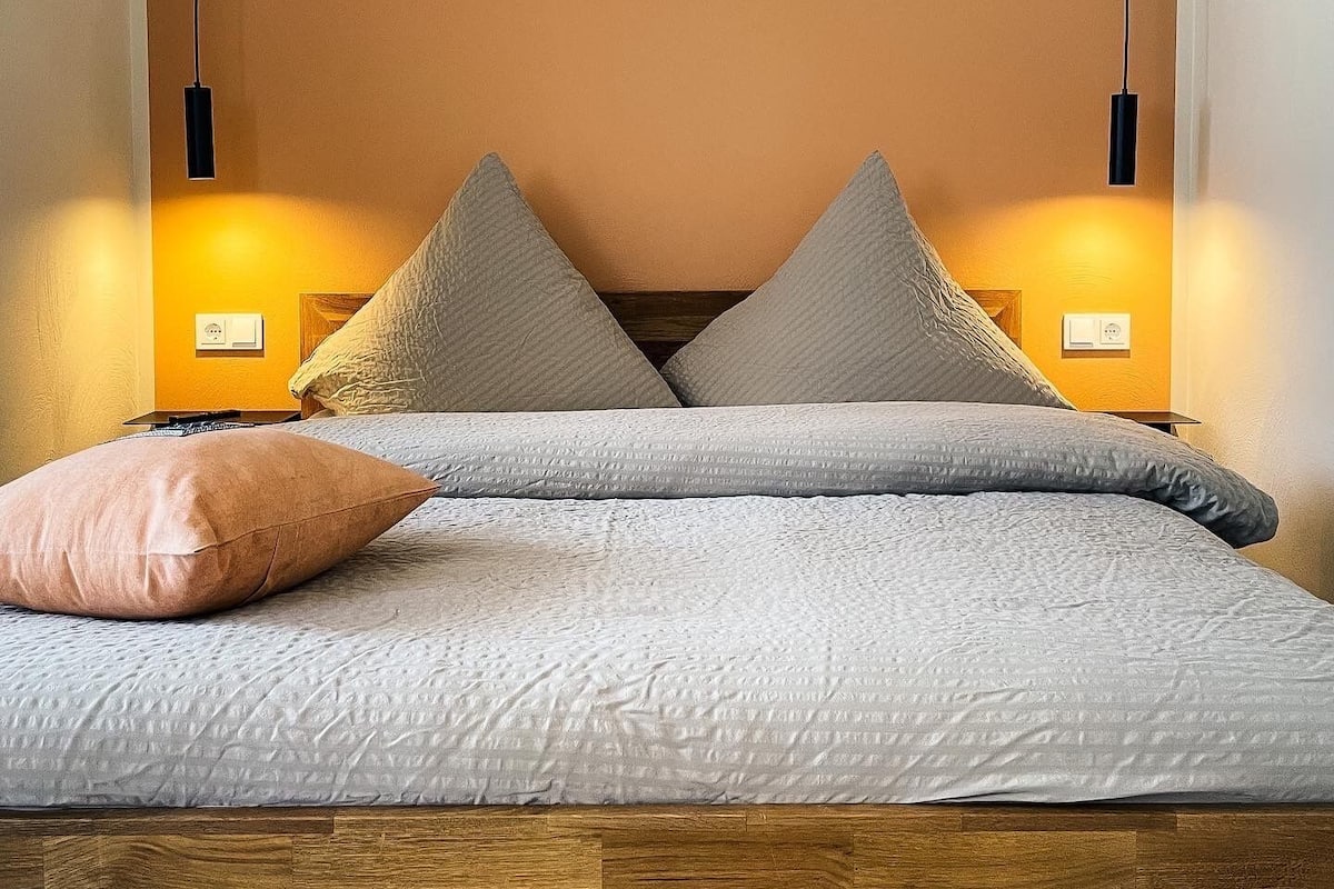 A bed with a wooden headboard, two bedside lamps, and a pillow.