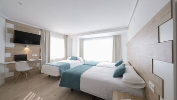 A modern hotel room with two beds, a desk, and a TV.