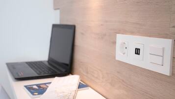A laptop on a desk with a map and a book, a wall socket, and a USB port.