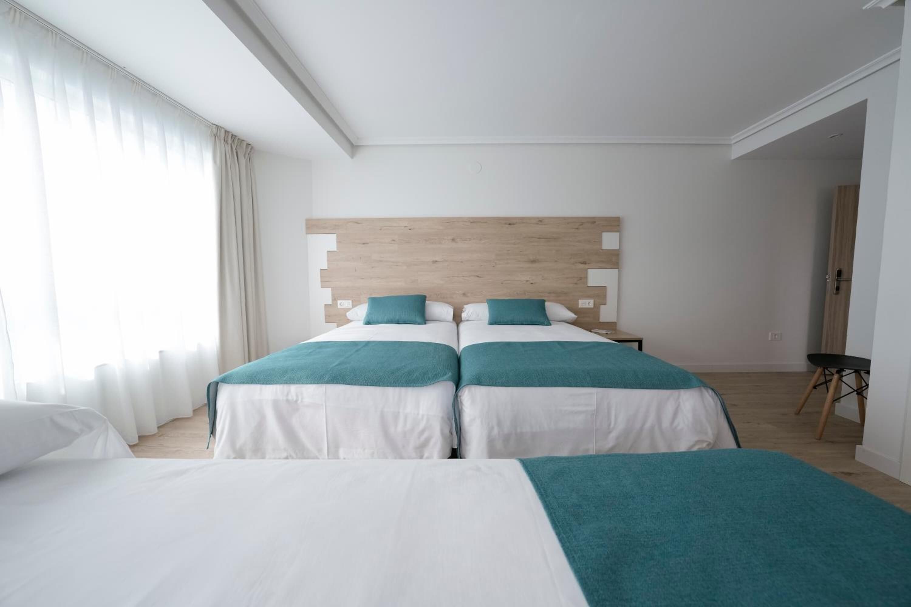 A hotel room with two beds, a wooden headboard, and a small table.