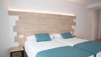 Una cama doble con cabecera de madera, dos almohadas color turquesa y una manta turquesa a juego.