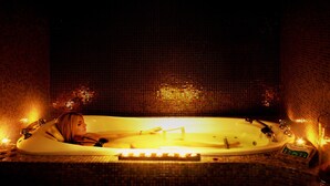 A woman relaxing in a bathtub with candles and a water heater. - Ax'Hotel (Chorges)