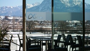 A hotel interior with a view of snow-covered mountains through large windows. - Ax'Hotel (Chorges)