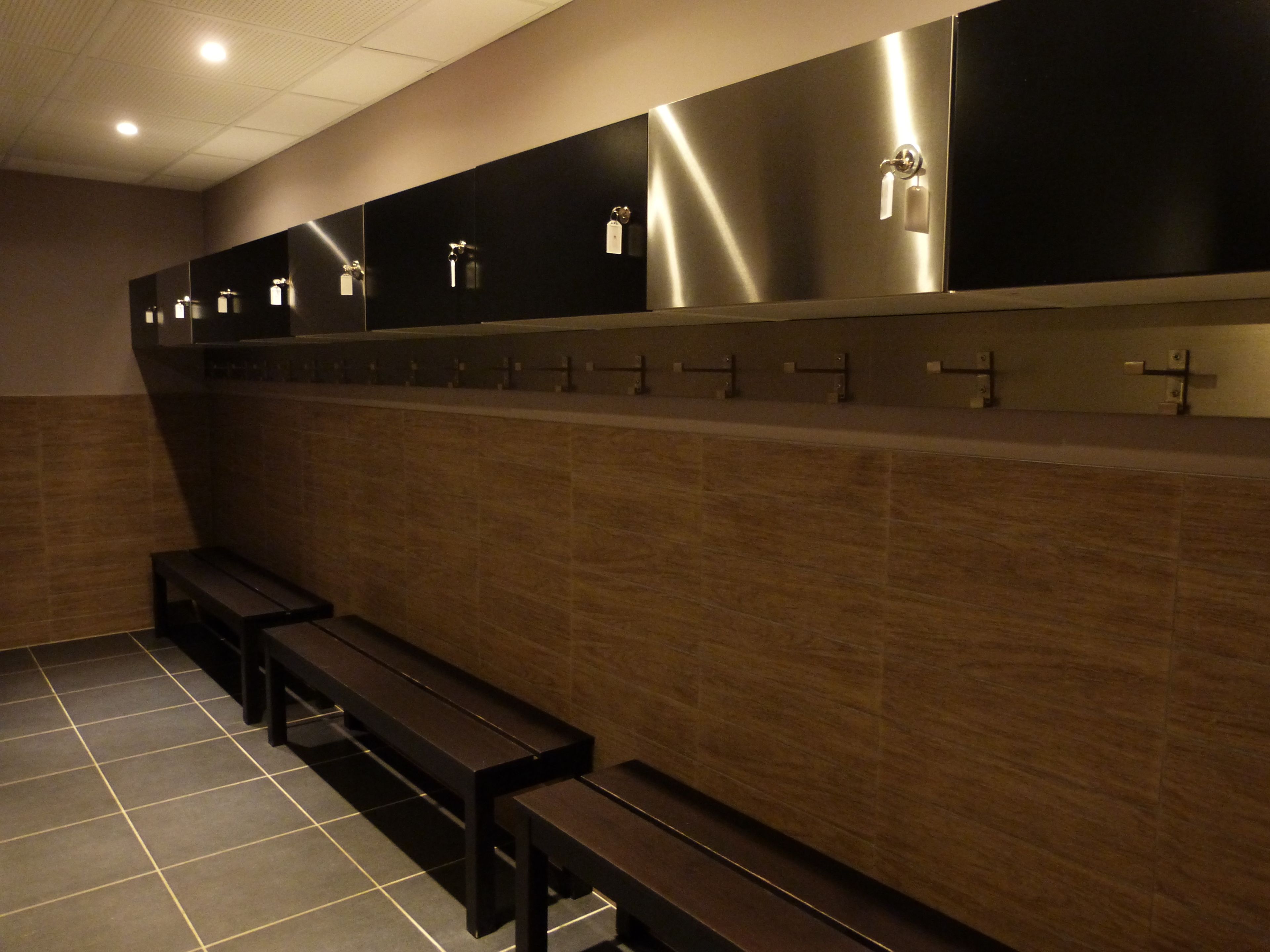 A restroom with multiple sinks, benches, and a tiled floor.