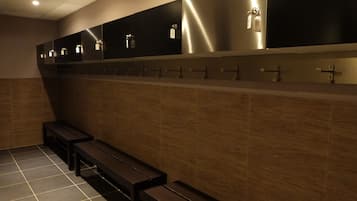 A restroom with multiple sinks, benches, and a tiled floor.