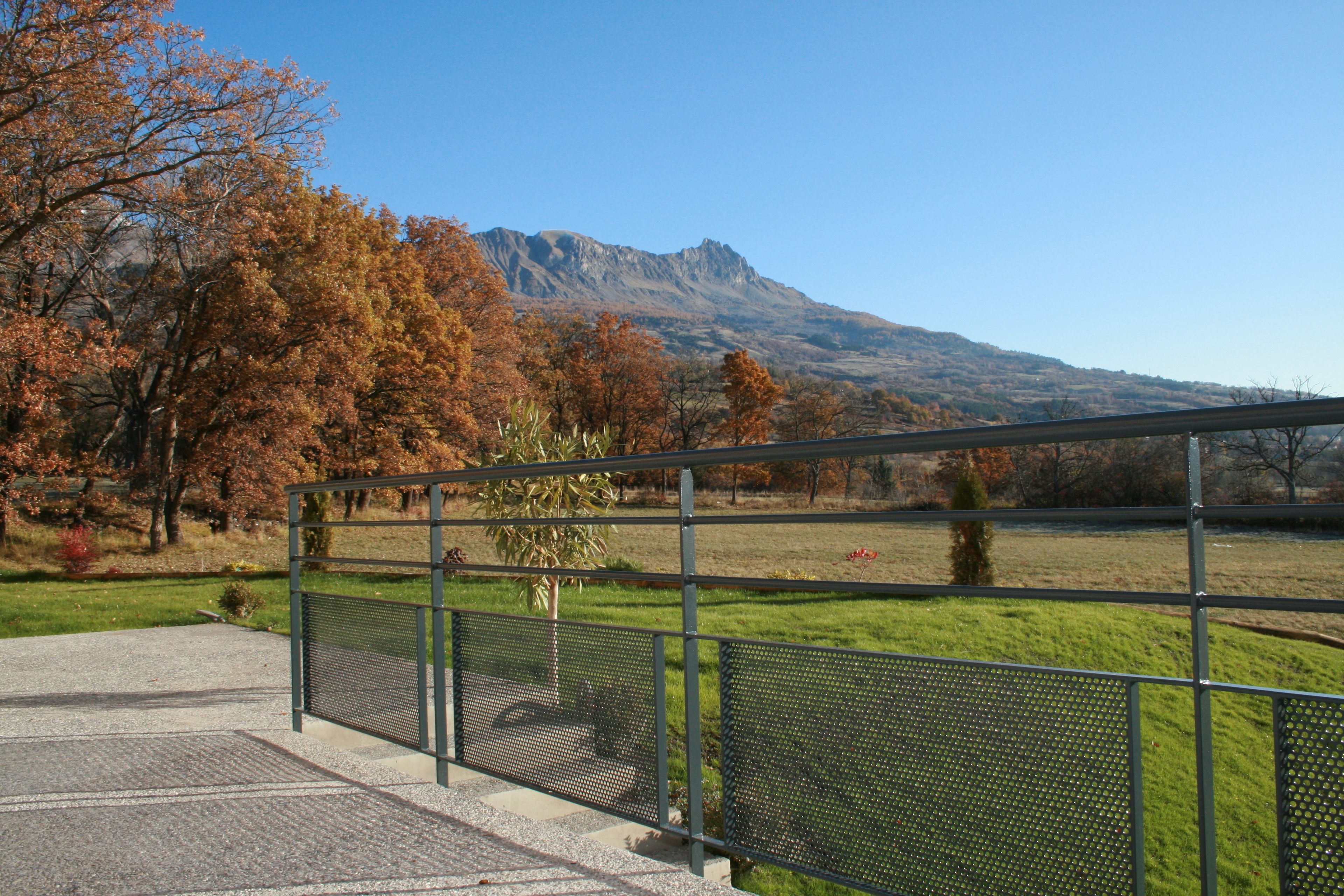 Vista de un paisaje montañoso con una valla metálica en primer plano.