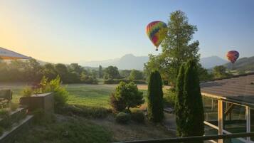 Vista panorámica desde un balcón que da a un jardín con globos aerostáticos a lo lejos.