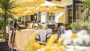 Een terras met gele parasols, tafels, stoelen en potplanten.