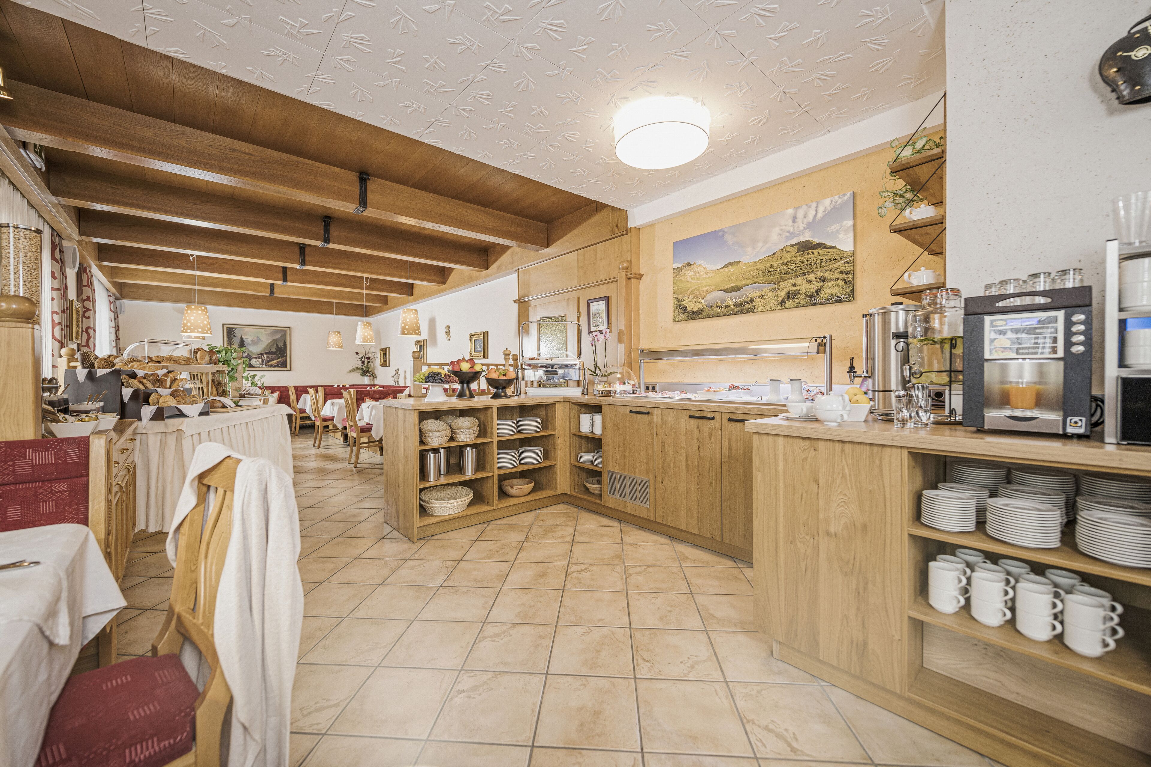 A restaurant with wooden beams, a kitchen area, and a dining area with tables and chairs.