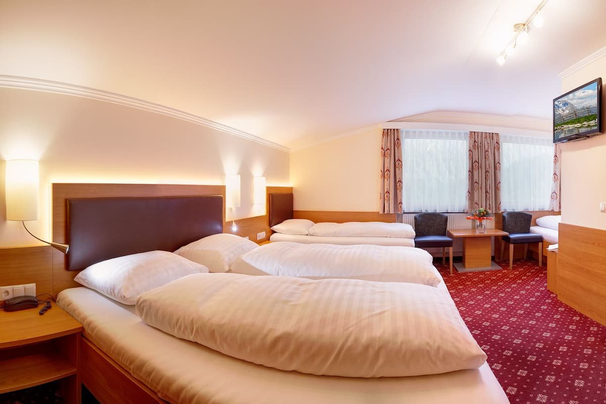 Habitación de hotel con una cama grande, mesitas de noche, un escritorio con una silla y un televisor en la pared.