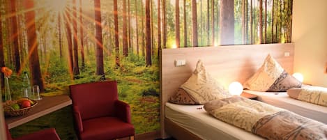 A room with a bed, red chairs, a shelf with fruits, and a forest mural on the wall.