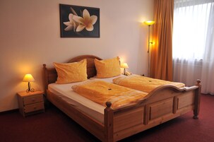 A double bed with a wooden headboard, two bedside tables with lamps, and a framed picture on the wall.