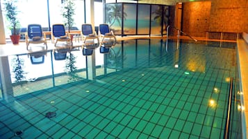 Una piscina techada, sillones reclinables de piscina