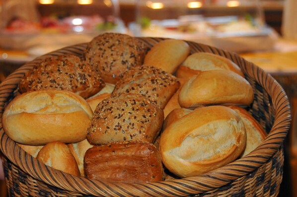 A basket filled with various types of bread, including rolls and seeded buns. - Hotel Niedersfeld (Winterberg)