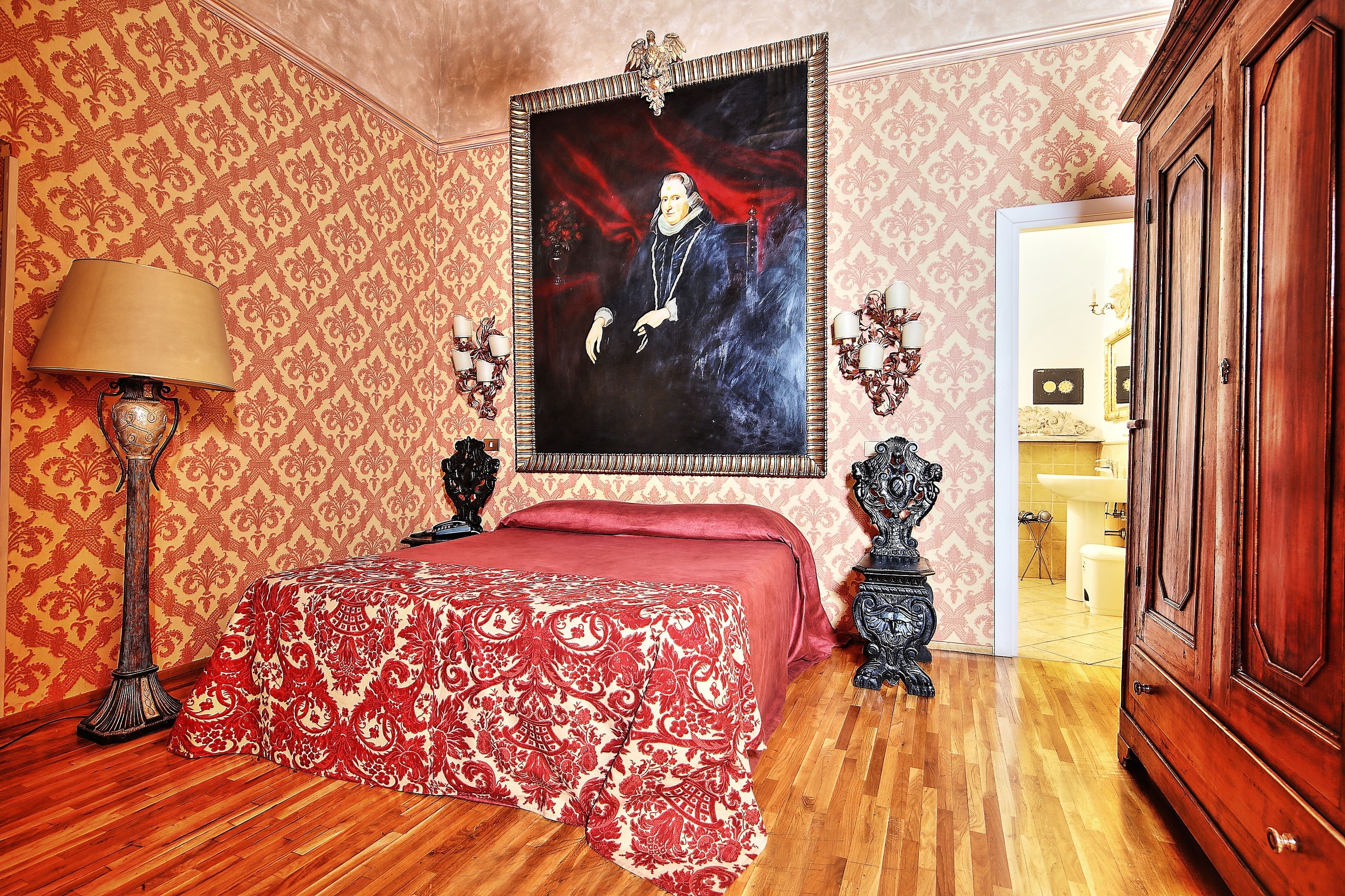 A bedroom with a bed, a lamp, a painting, and a wardrobe.