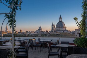 A terrace with outdoor seating and a view of historic buildings. - Antica Dimora Dell'Orso (Rome)