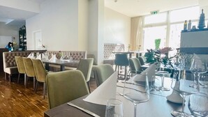 Un ristorante con pavimento in legno, sedie imbottite e tavoli apparecchiati per la cena.