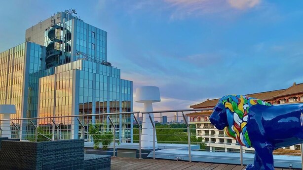 Un edificio moderno con facciata in vetro e una scultura blu su un terrazzo.