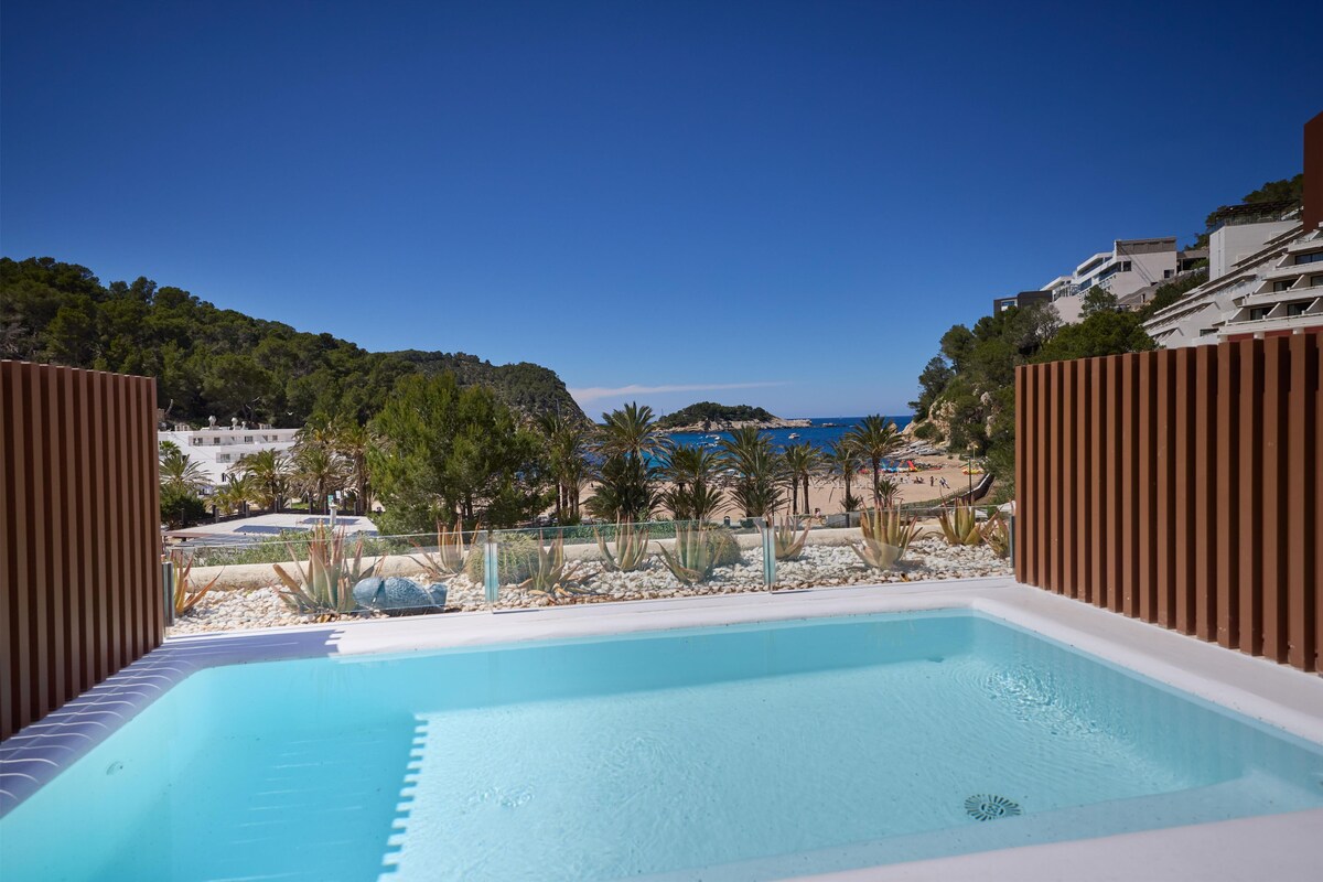 A pool area with a clear view of a beach and a mountainous landscape.