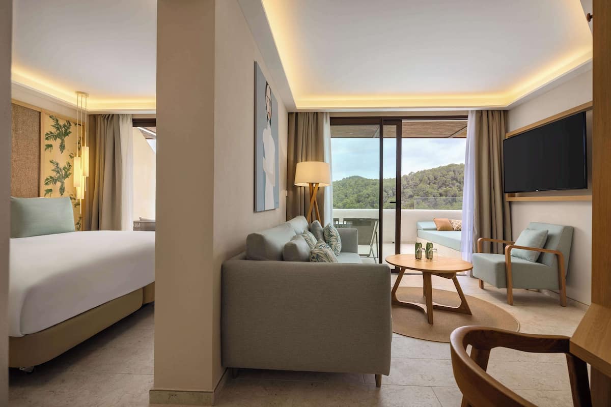 Une chambre d’hôtel équipée d’un lit, d’un canapé, d’un fauteuil, d’une table et d’un téléviseur.