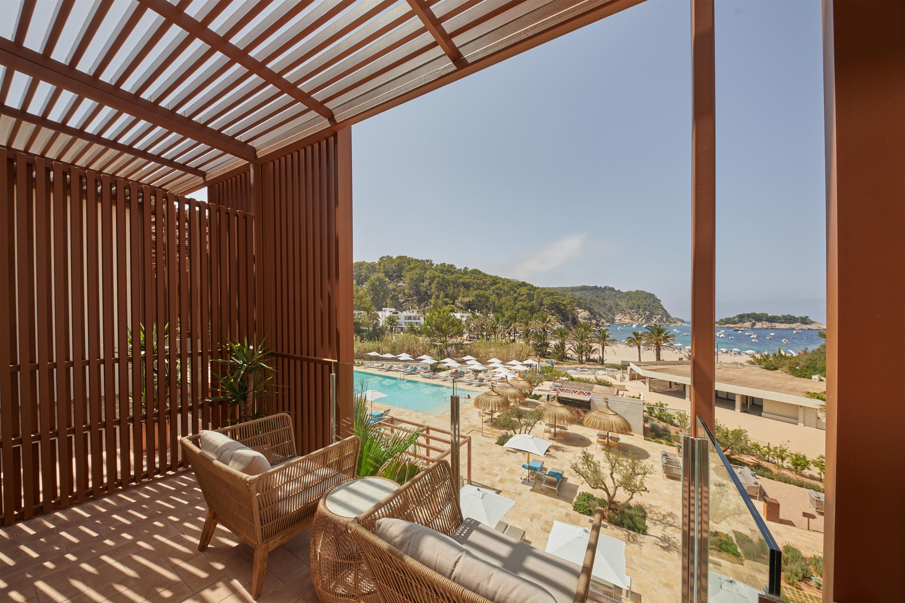 Ein Balkon mit Korbmöbeln, einem Pool und Blick auf den Strand.