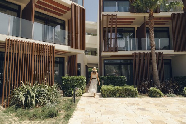 A modern building with a central courtyard, a palm tree, and a person walking.