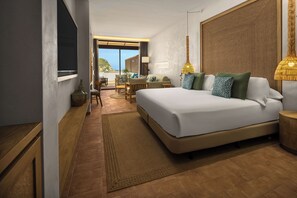 A modern hotel room with a large bed, a dining area, and a view of the outdoors.