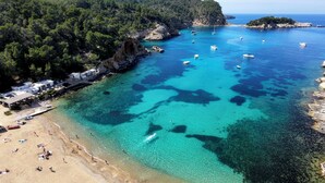 A coastal area with clear turquoise waters, boats, and a beach with people. - Cala San Miguel Ibiza Resort, Curio Collection by Hilton (Sant Joan de Labritja)
