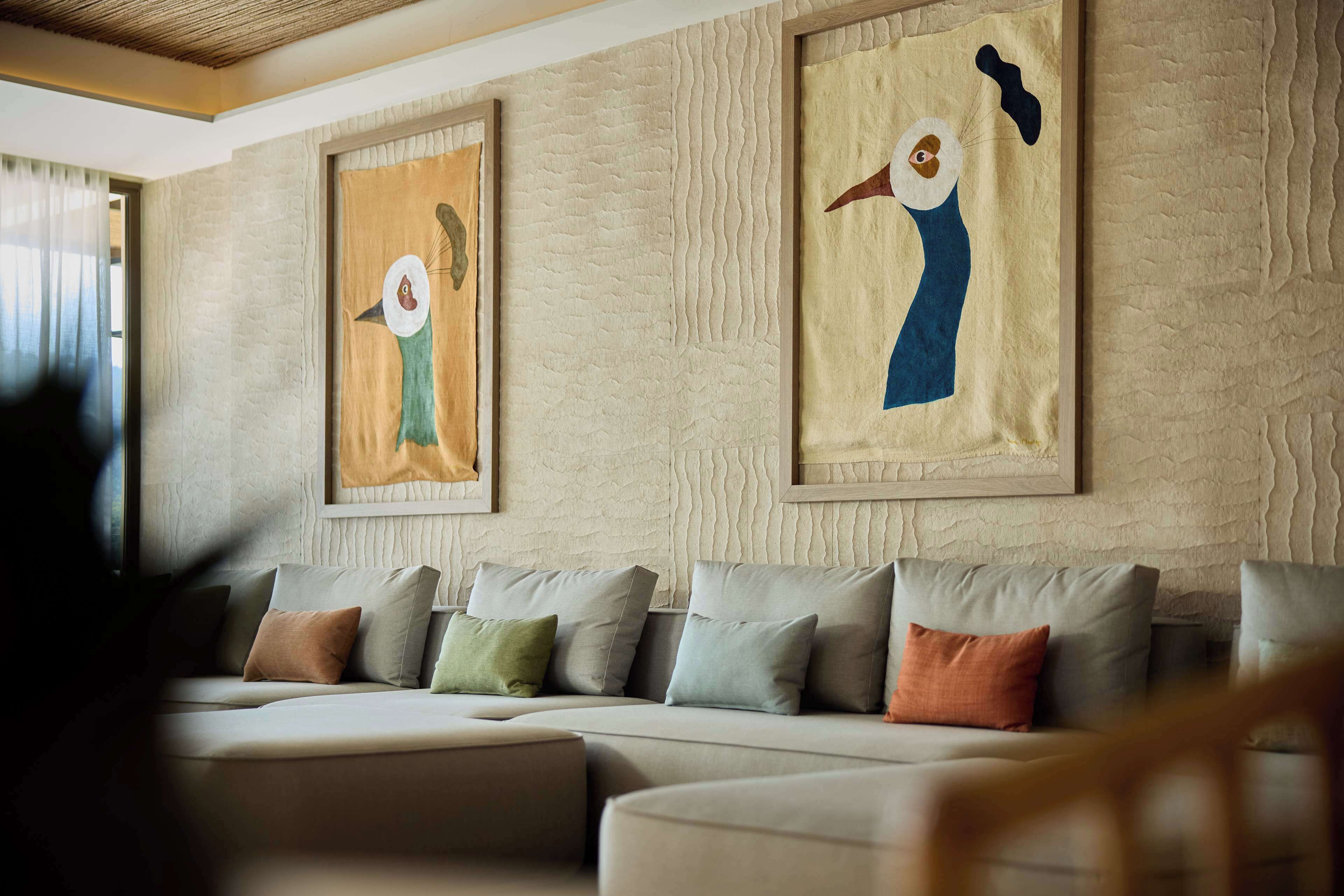 A modern living room with a sectional sofa, framed abstract paintings, and a textured wall.