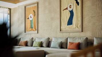 A modern living room with a sectional sofa, framed abstract paintings, and a textured wall.