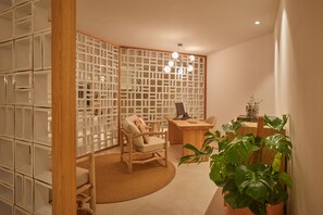 A room with a wooden desk, a chair, a potted plant, and a partition with storage cabinets.