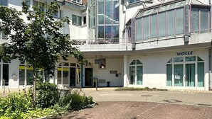 A hotel with a central courtyard, multiple floors, and a prominent 'WOLLE' sign. - Hotel Aichtaler Hof (Aichtal)