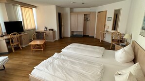 A hotel room with a large bed, a desk with a chair, a television, and a wardrobe. - Hotel Aichtaler Hof (Aichtal)