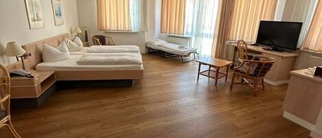 Een ruime woonkamer met een zithoek, een eettafel en een televisie.