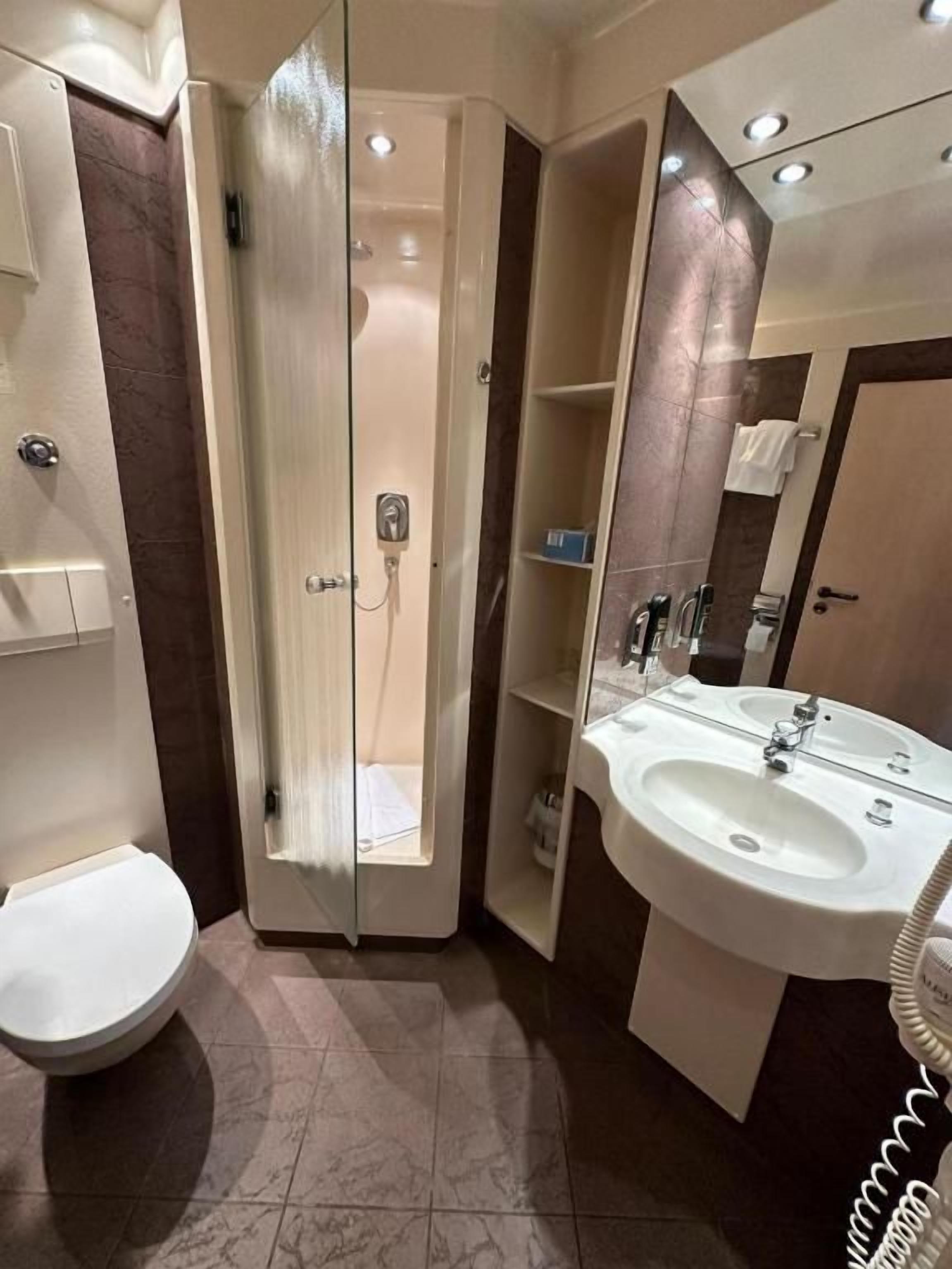 Un baño con inodoro, cabina de ducha y lavamanos.
