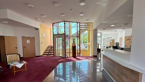 A spacious lobby with a red carpet, a reception desk, and a staircase leading to upper floors. - Hotel Aichtaler Hof (Aichtal)