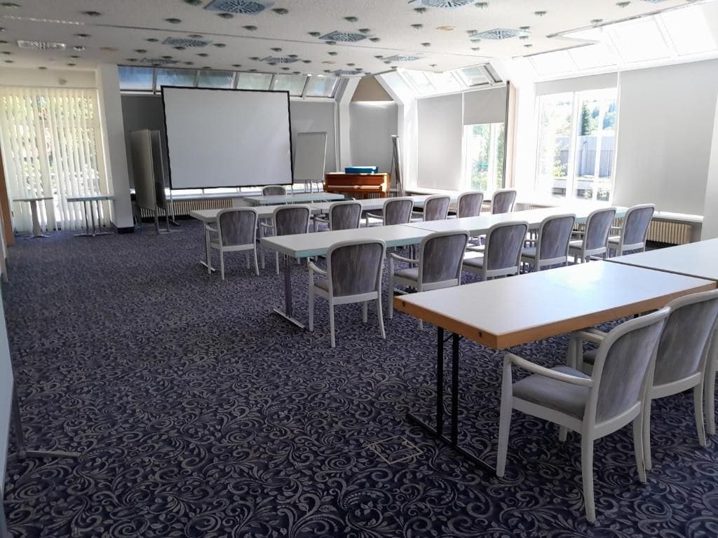 A conference room with a long table, chairs, a whiteboard, and a piano.