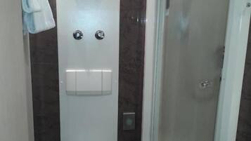Een badkamer met een toilet, een douchecabine en een handdoek aan de muur.