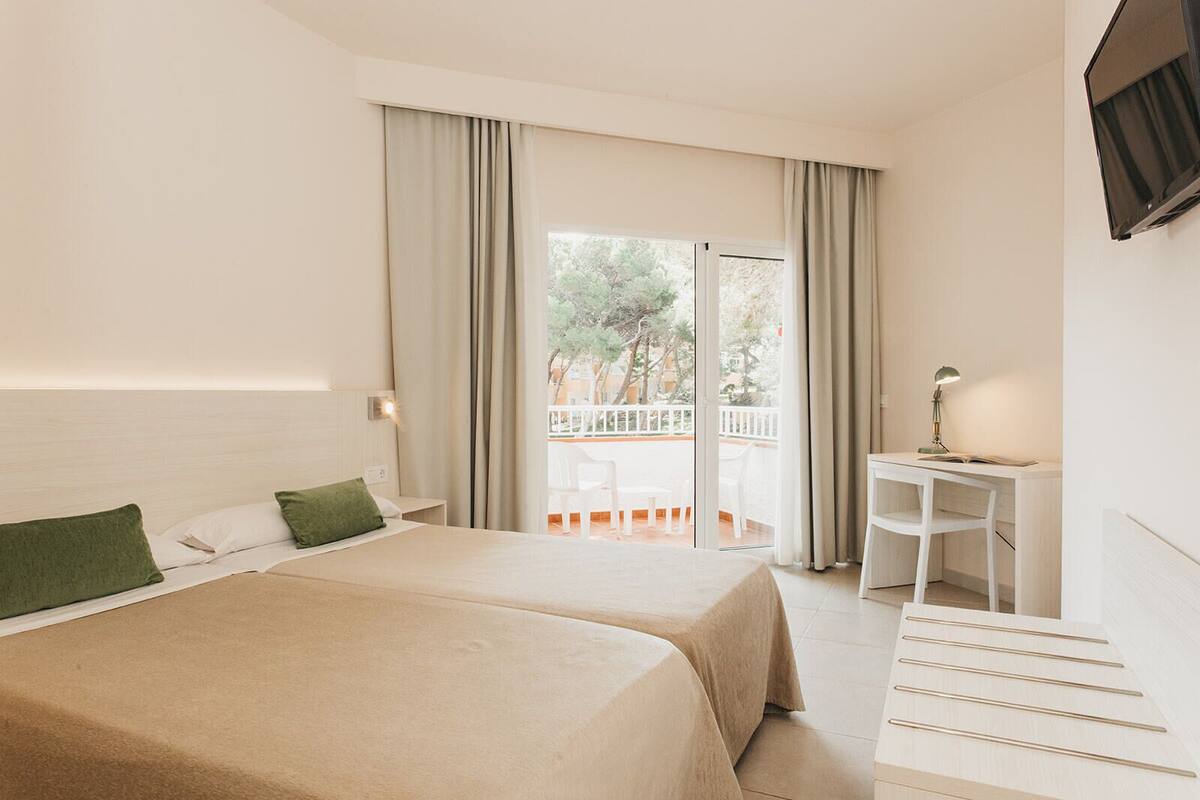 Une chambre d’hôtel avec deux lits, un bureau, une chaise et un balcon avec vue.