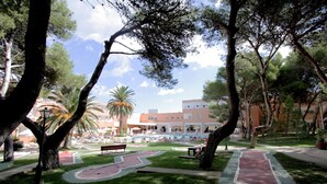 Un parque con piscina, bancos y un edificio al fondo.