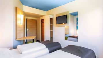 Habitación de hotel con dos camas, un televisor montado en la pared y una puerta de madera.