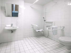Un baño moderno con azulejos blancos, un lavabo, un inodoro y una zona de ducha.